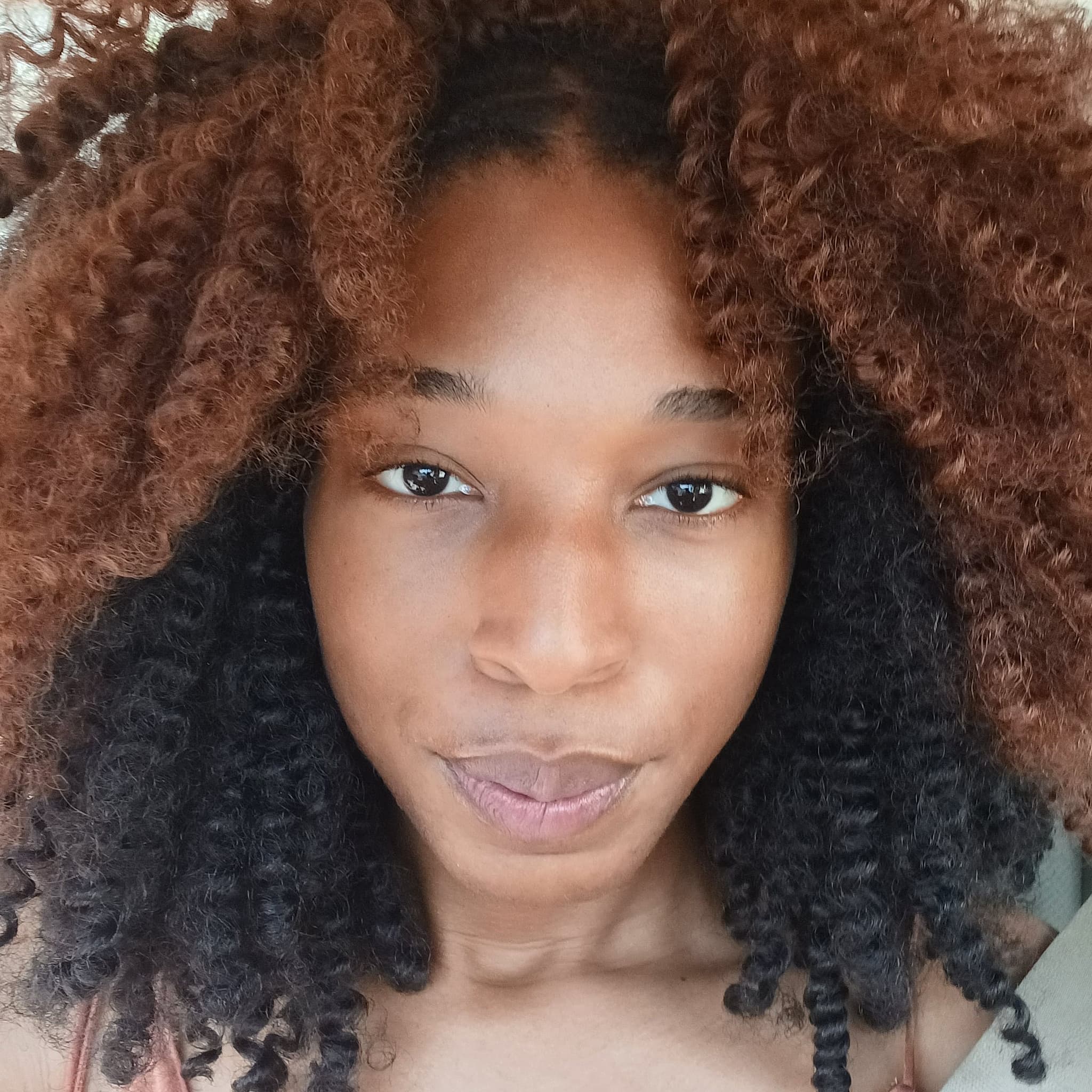 Headshot of Sultana Isham shows a close-up image of the artist who smiles at the camera. She has voluminous two-toned hair that is brown and black.