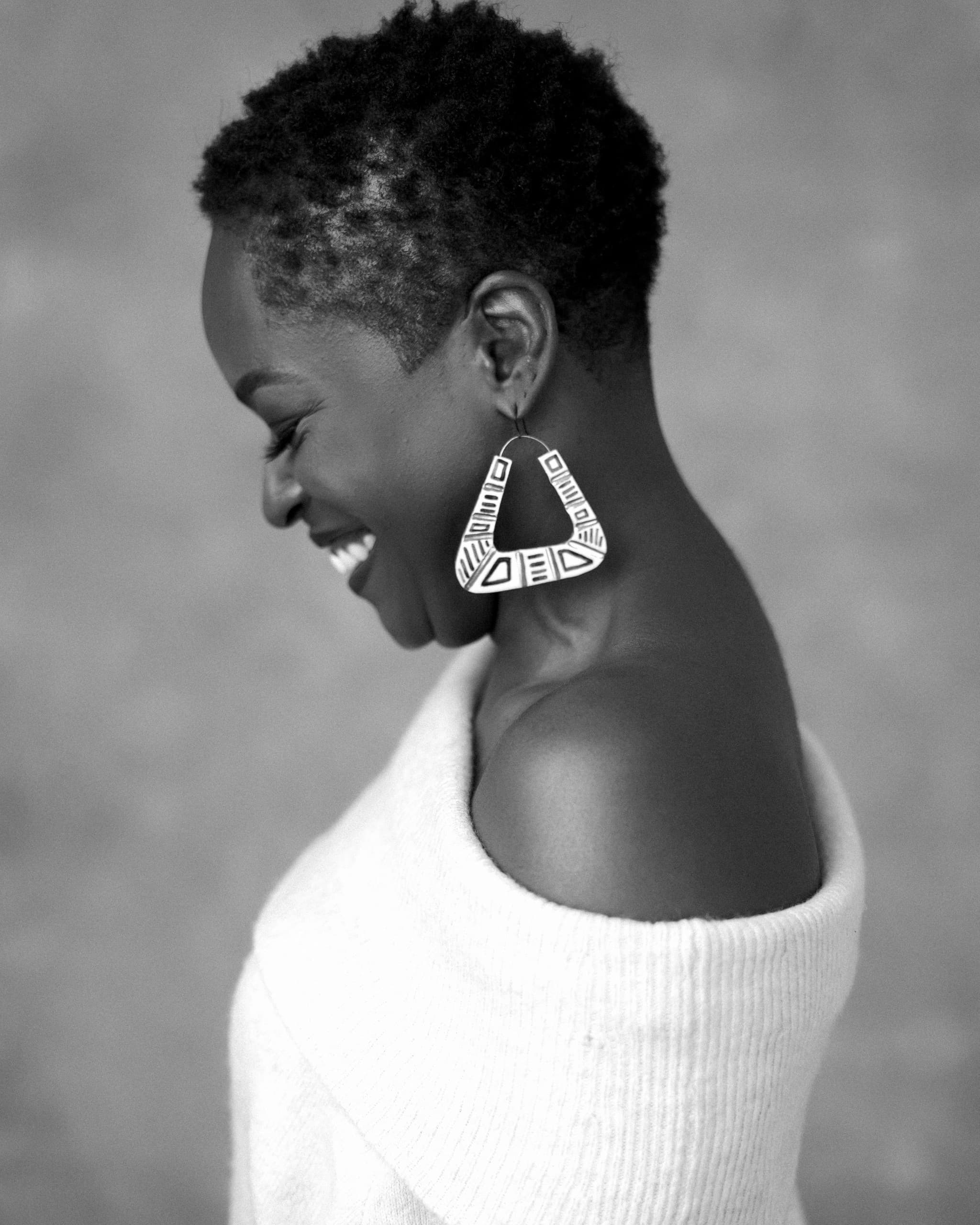 Yaba Blay laughs and looks down, wearing a white hop.