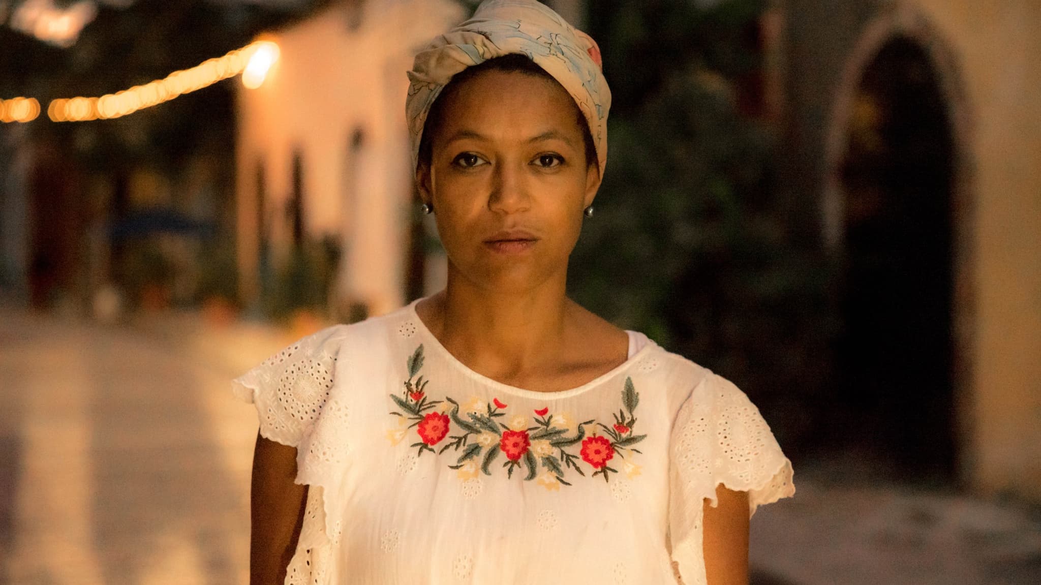 A headshot of Anisia Uzeyman, she is a Black woman. She is wearing a linen shirt, her hair is wrapped.