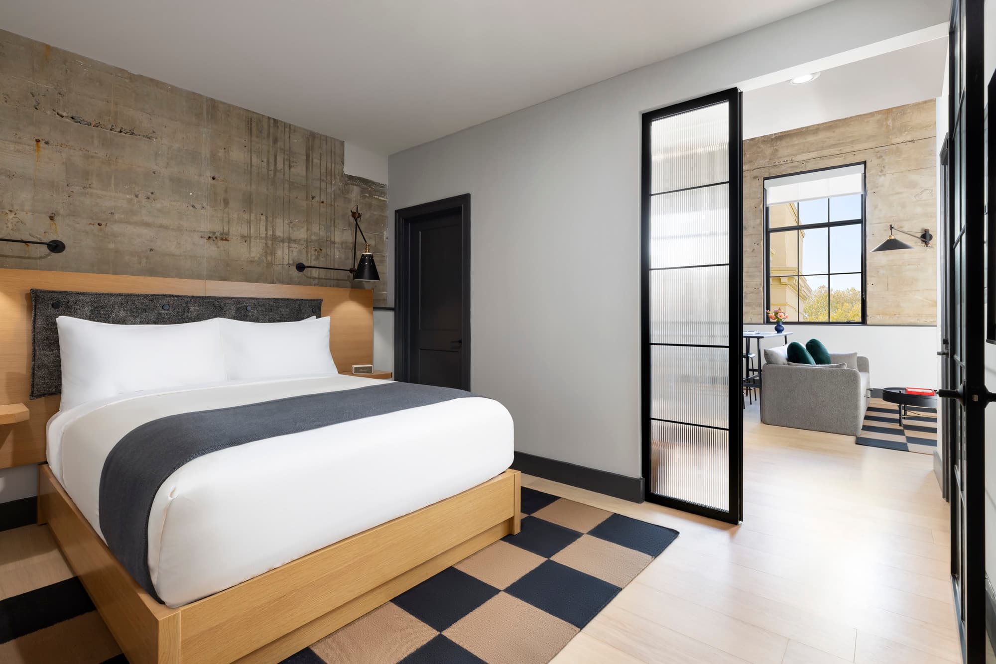 A photo of the inside of a large hotel room, featuring a bed and living area.