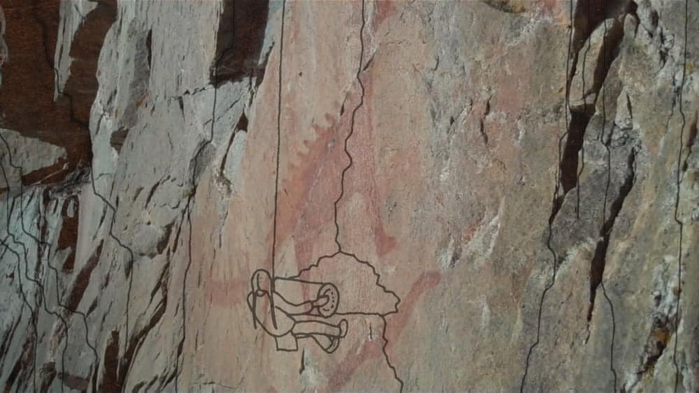 A line drawing from “INAATE/SE/ of a little man climbing up a mountain.