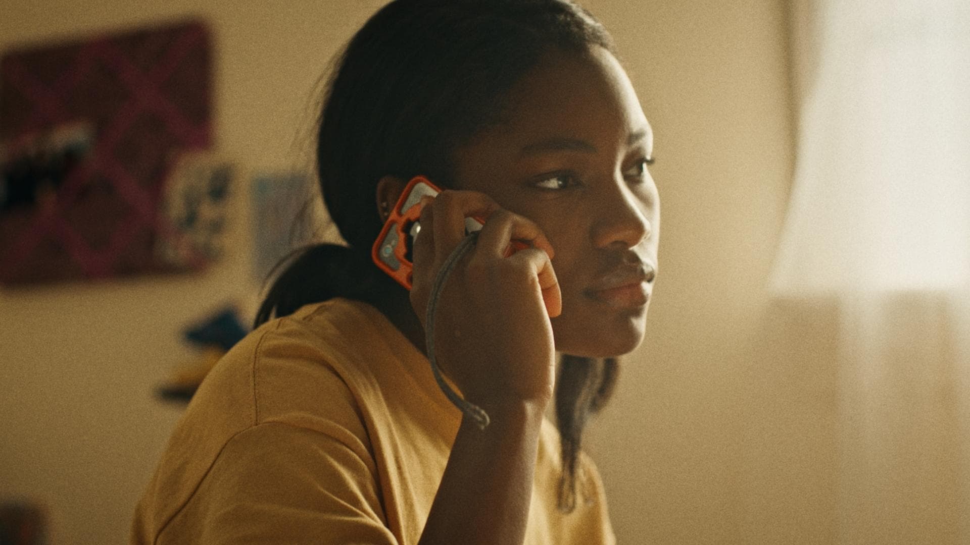 A film still from Hatchlings shows a young black girl holding her phone up to her ear. Her gaze is fixed off screen.