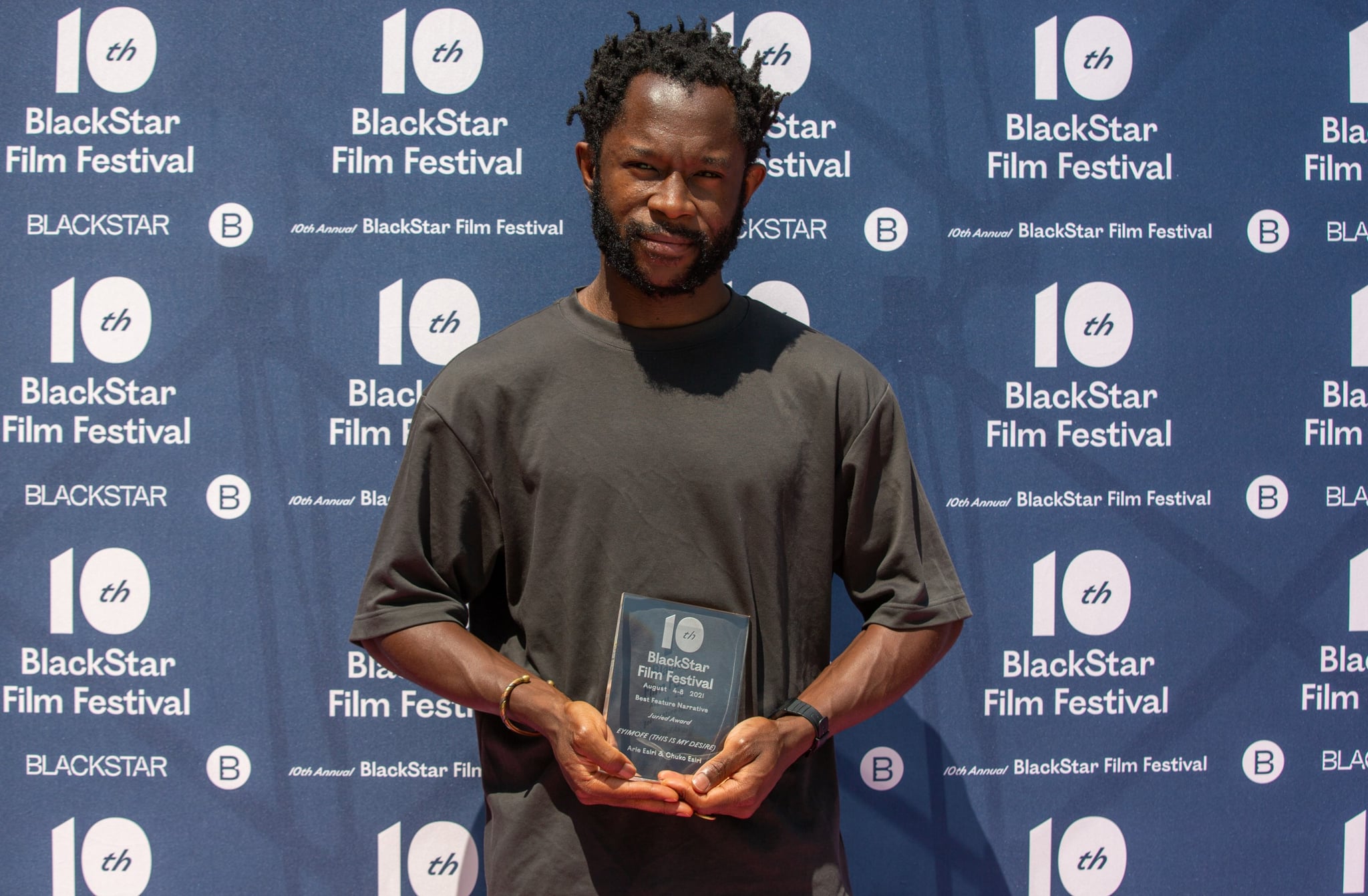 Photo of filmmaker Arie Esiri holding up his award for Best Feature Narrative at the 10th Annual BlackStar Film Festival.