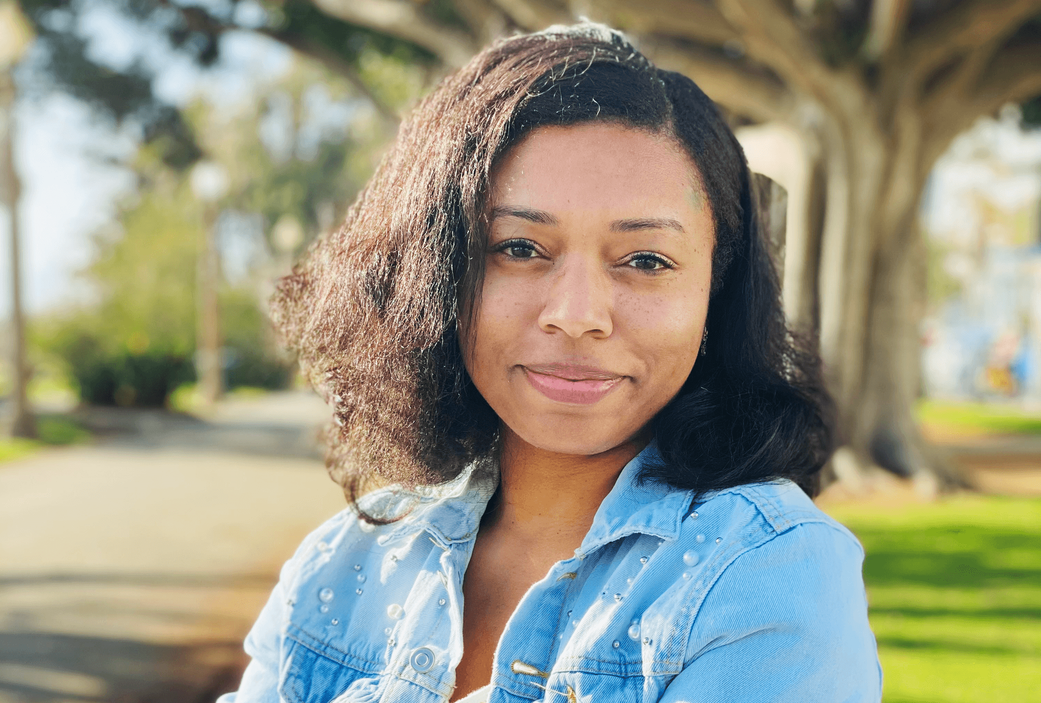 A headshot of Nijla Mu'min. She is a Black woman. She is smiling softly at the camera.