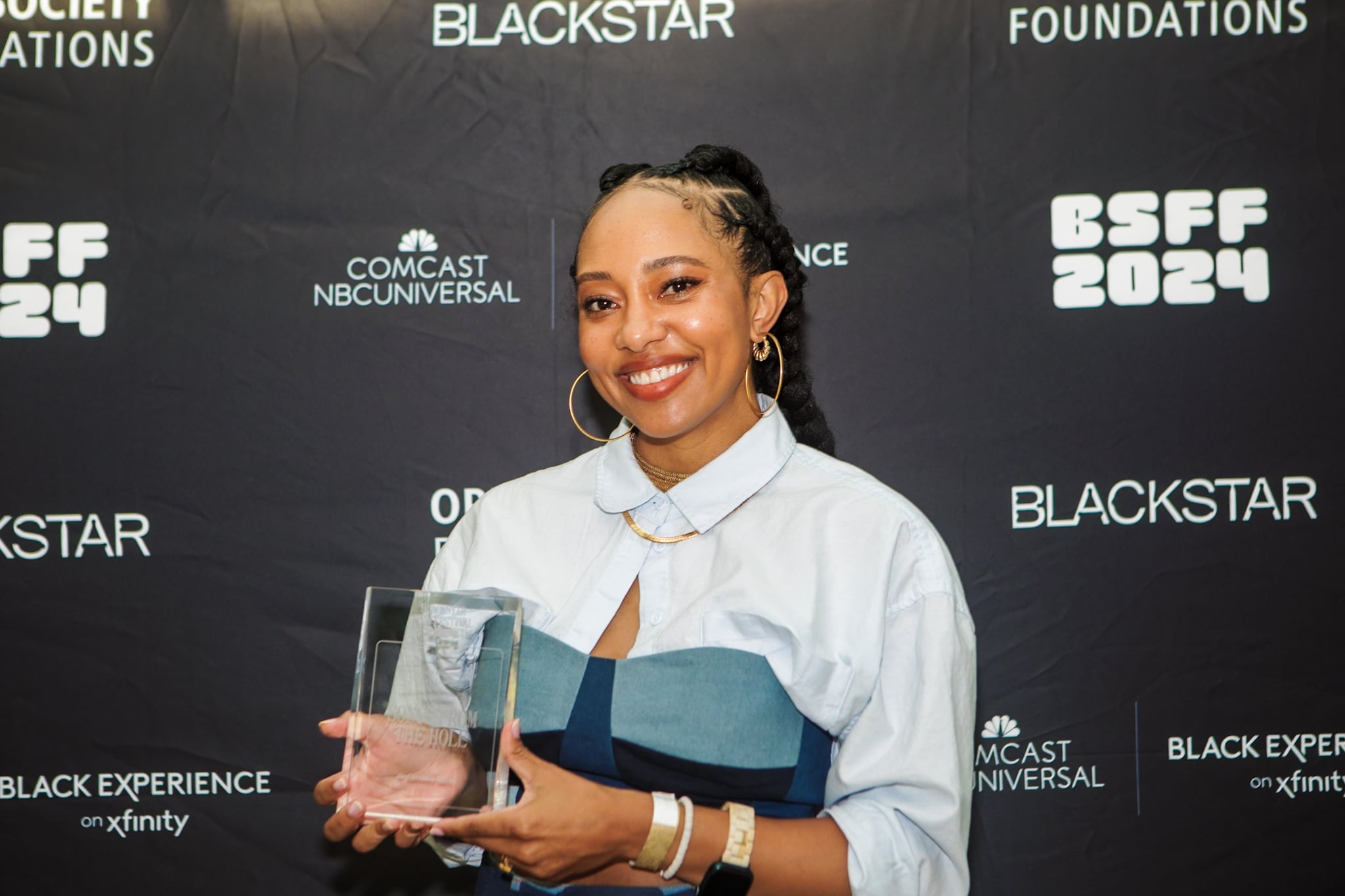 Photo of Contessa Gayles posting in front of a black step and repeat featuring the logos BSFF2024, BlackStar, Comcast NBC Universal, and Open Society Foundations.