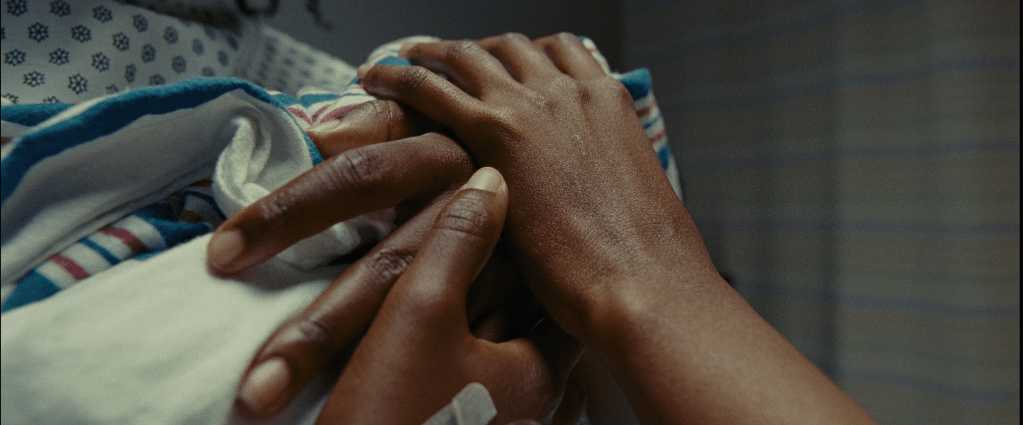 A close up photo of two hands holding each other as well as a blue, white, and red towel or piece of cloth.