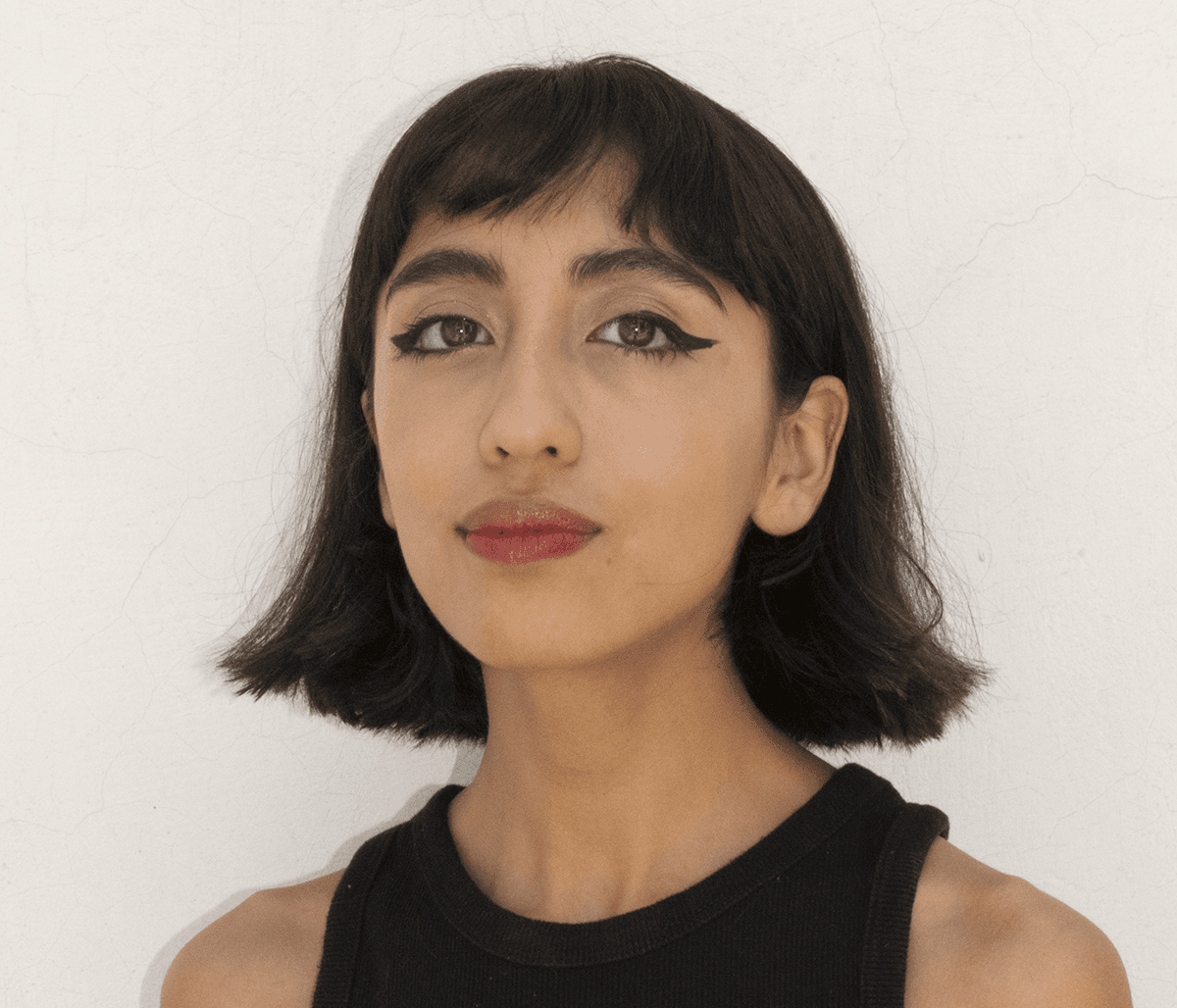 A headshot of Mir Rosales. Mir is Mexican. They have short straight hair. They are looking at the camera with a soft expression.