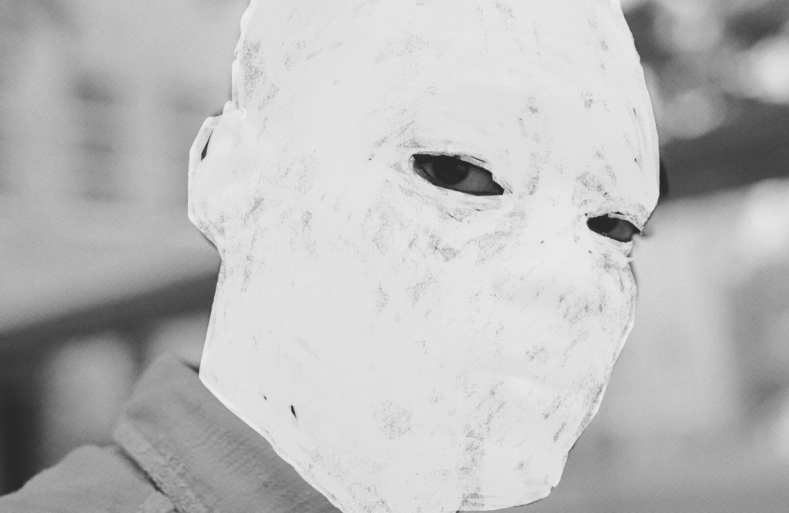 A still from the film Nickel Boys (2024). A black and white close-up of a person with only his eyes visible, his face is whited out.