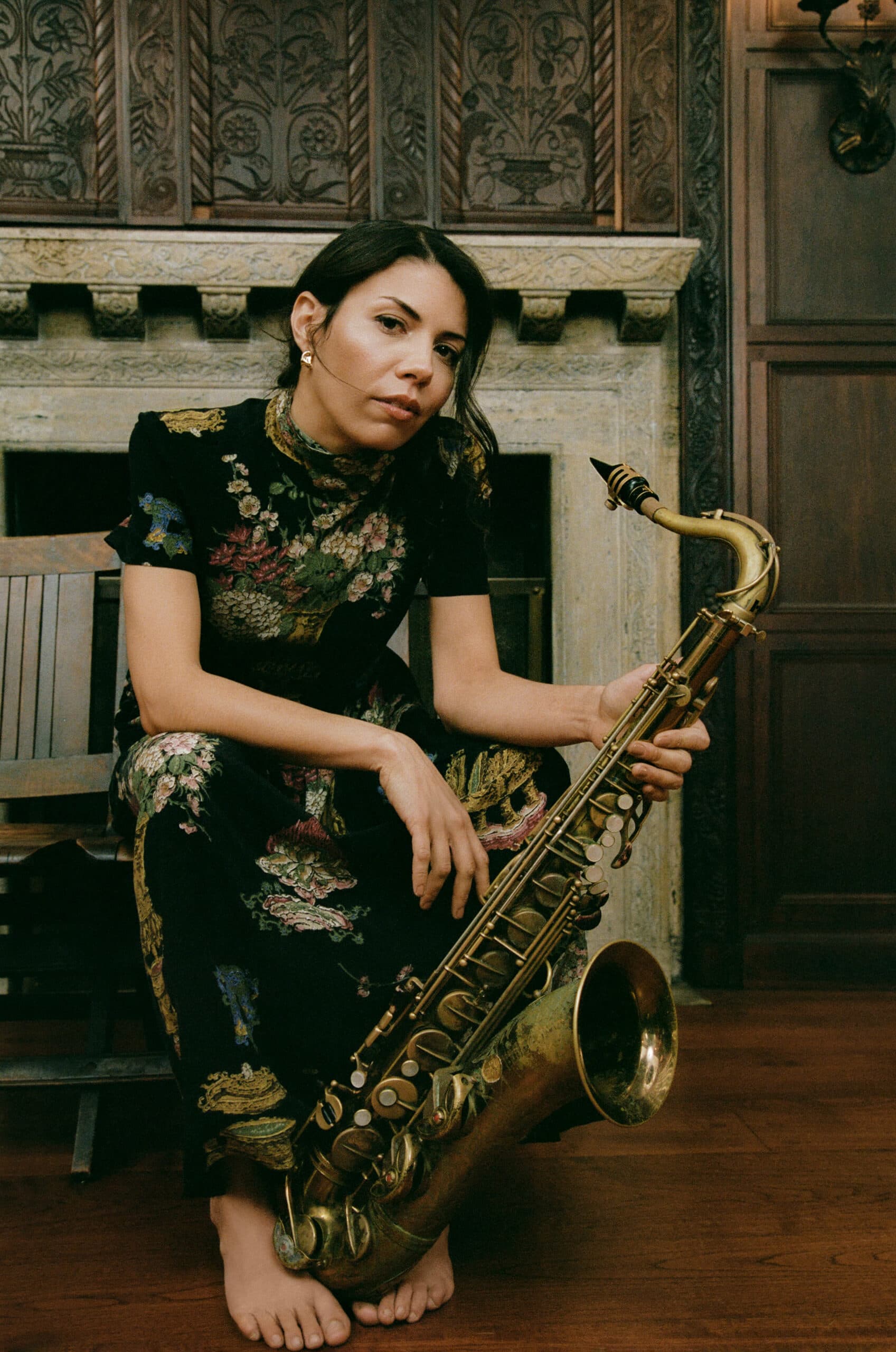 A headshot of Melissa Aldana. She is a woman of color, she is holding a saxophone.